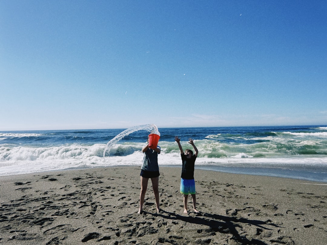 Two children playing with water on a sunny beach.