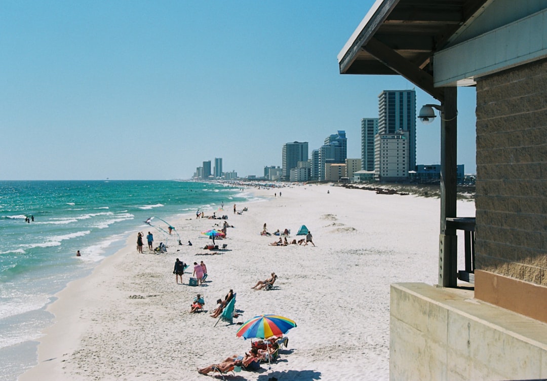 People relaxing on a sunny beach with city skyline.