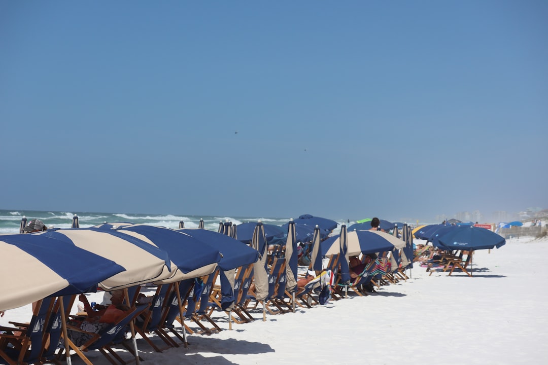 A row of blue beach umbrellas and loungers on the white sand at Destin, Florida