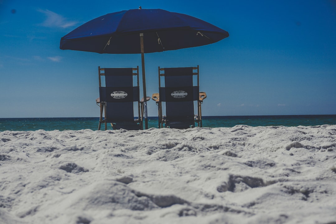 Two beach chairs under an umbrella on the white sand at Destin, Florida