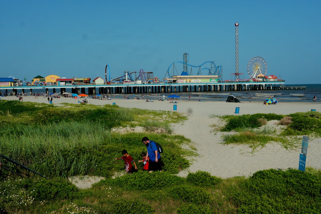 A family on the beach beside the Galveston Island Historic Pleasure Pier in Texas