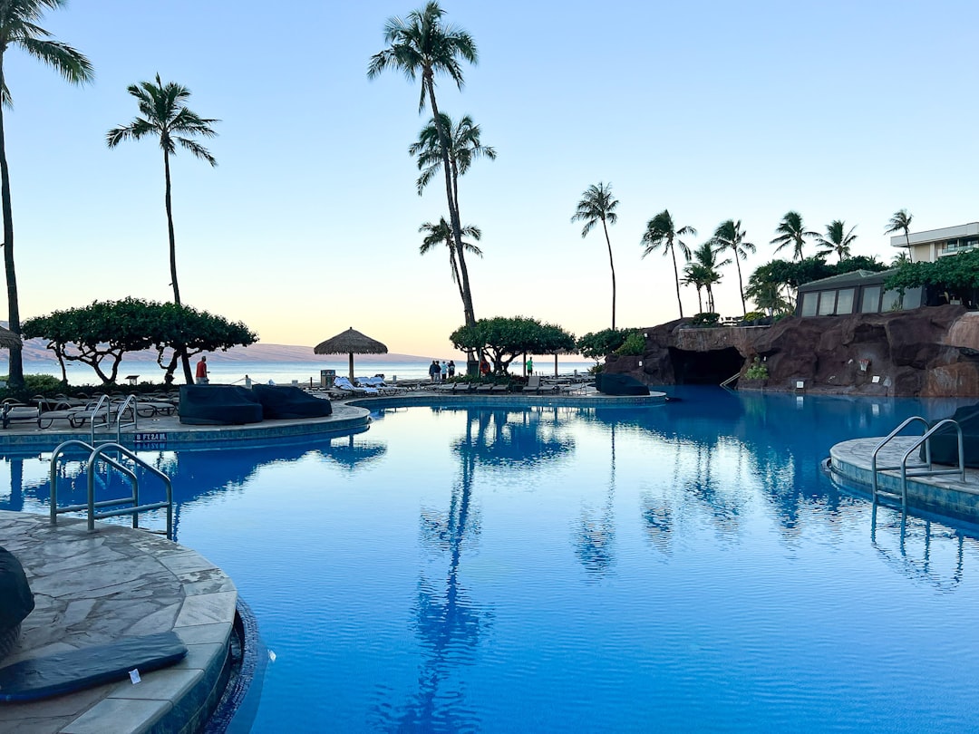 A resort pool with a lava grotto and a neighbouring island at dusk near Lahaina, Maui