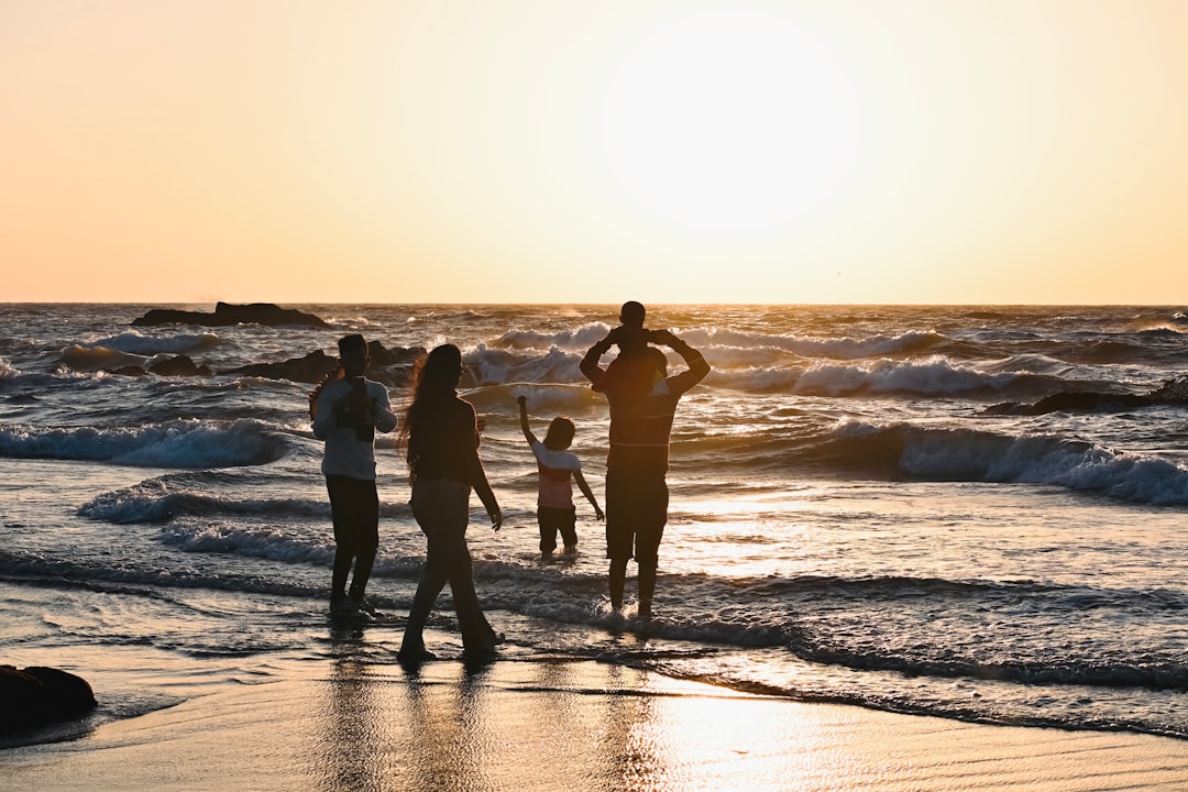 A group of people standing on top of a beach next to the ocean