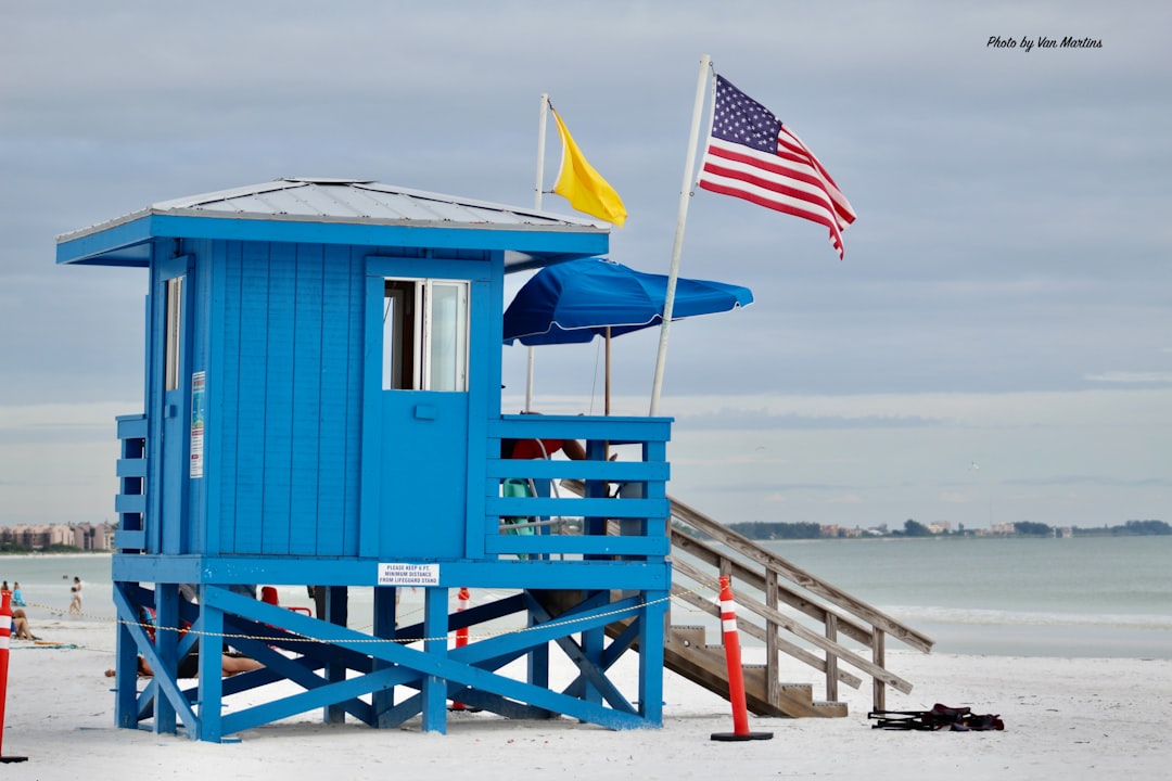 A blue lifeguard stand with flags on the white sand at Siesta Key, Florida