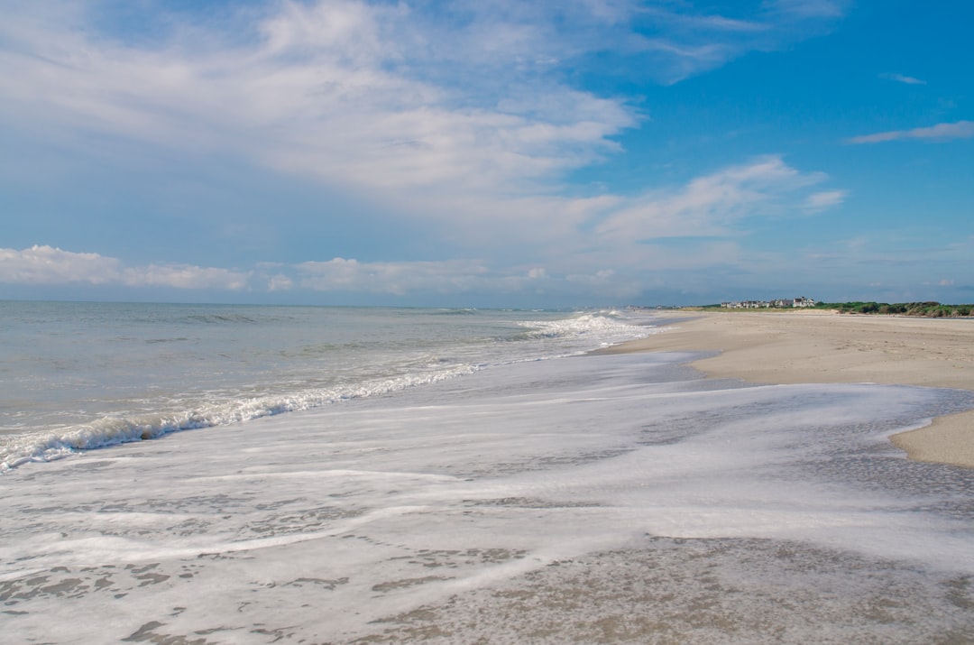 Waves crash on a sandy beach under a blue sky.