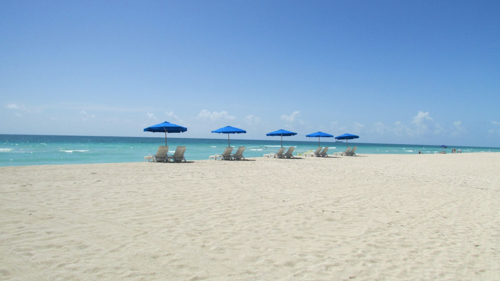 Brilliant white quartz sand and turquoise Gulf water with blue beach umbrellas, Sarasota Florida