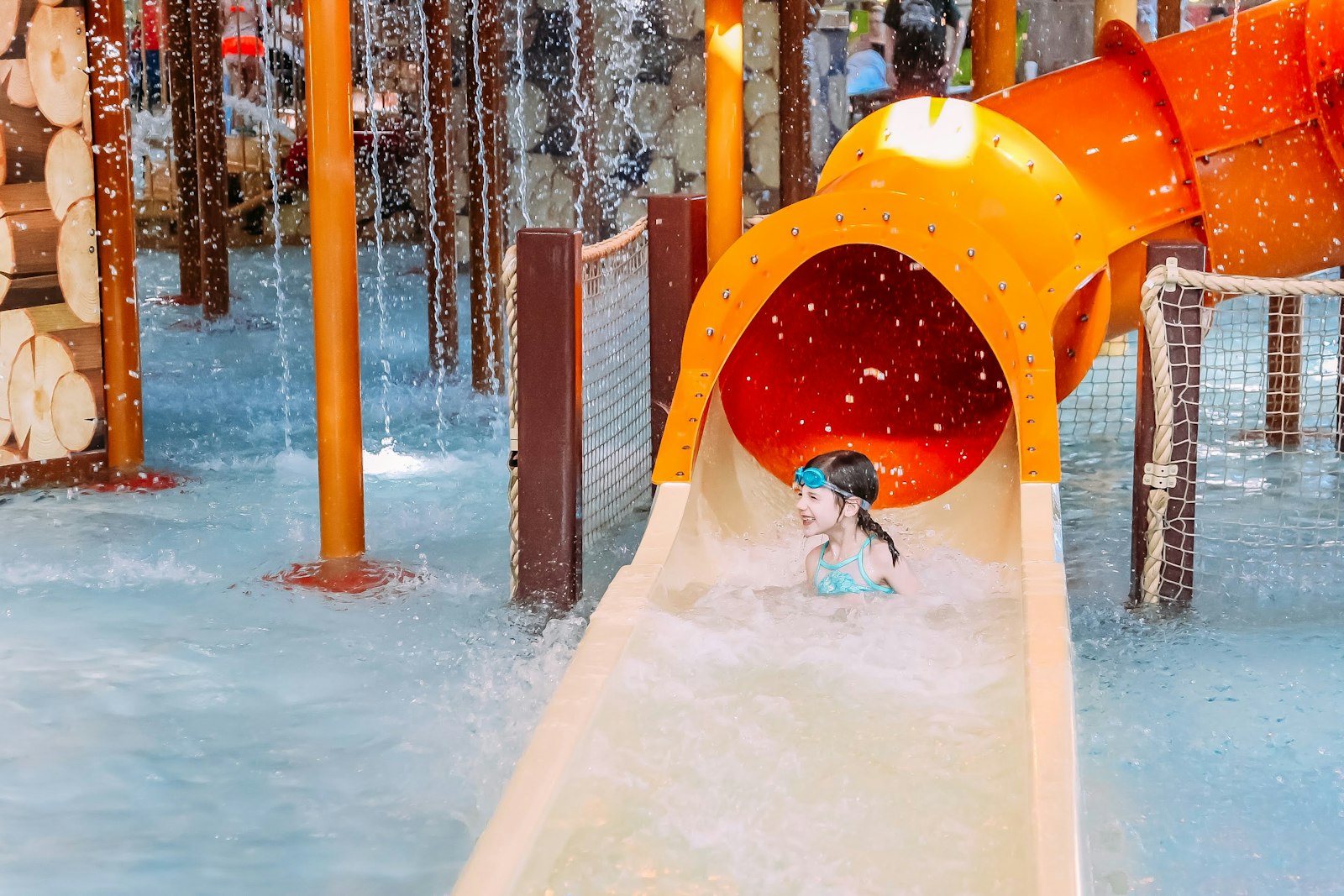 Child riding a water slide into an indoor hotel waterpark with log lodge styling