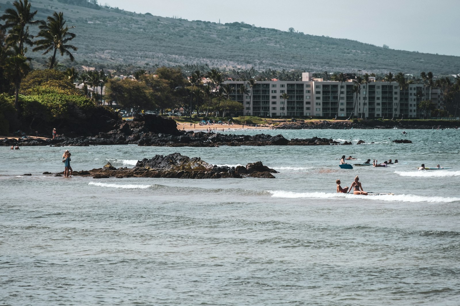 Families in the water below the West Maui mountains at Kihei, Hawaii